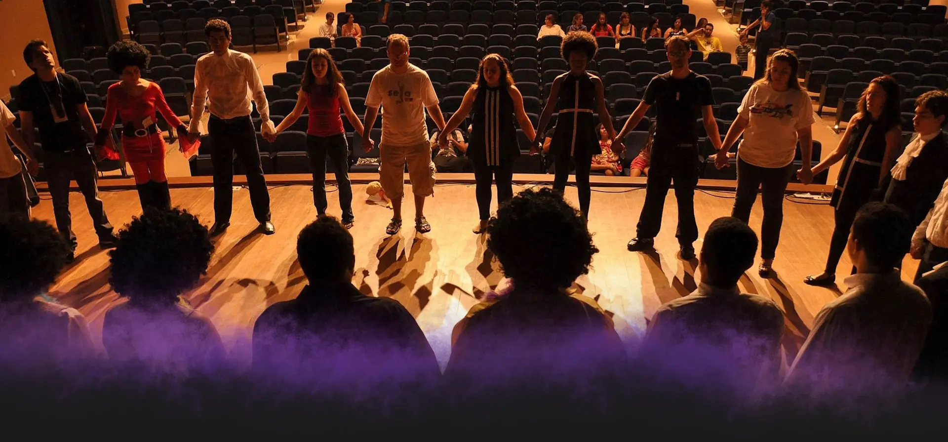 A group of people standing on the floor in front of purple lights.